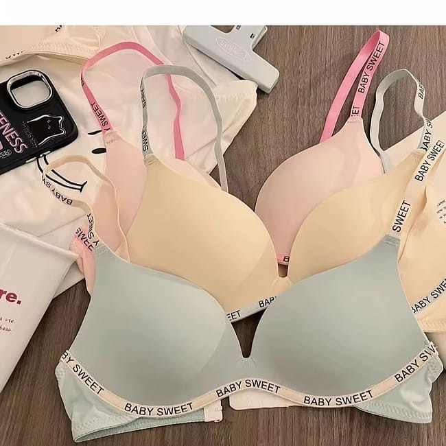 A stack of four pastel-colored wireless bralettes with "BABY SWEET" written on the straps.